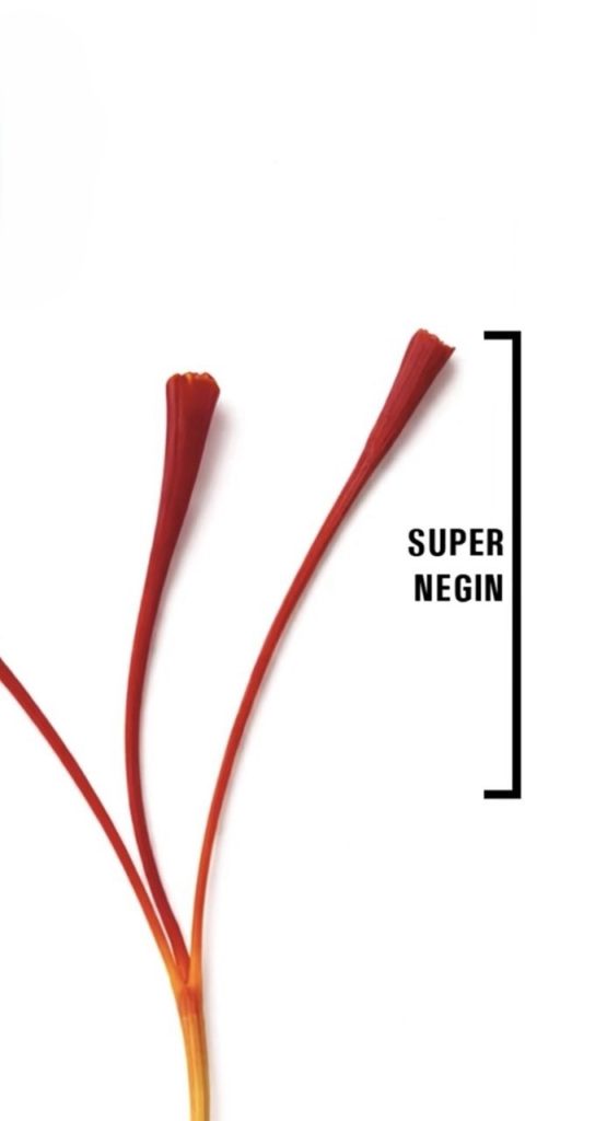 Close-up of Grade 1 Super Negin saffron threads showing deep crimson colour and characteristic trumpet-tipped stigmas on a white marble surface